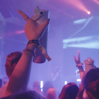 Hände mit BRITA LARQ iQ Flaschen werden in die Luft gestreckt, tanzende Menge vor Lichtshow.