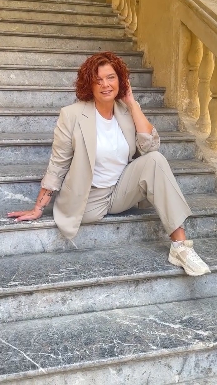 Frau mit Locken sitzt auf einer Marmortreppe