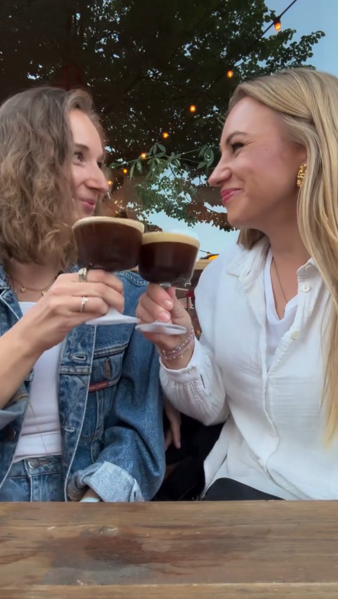 Zwei Frauen schauen sich lächelnd an und stoßen an